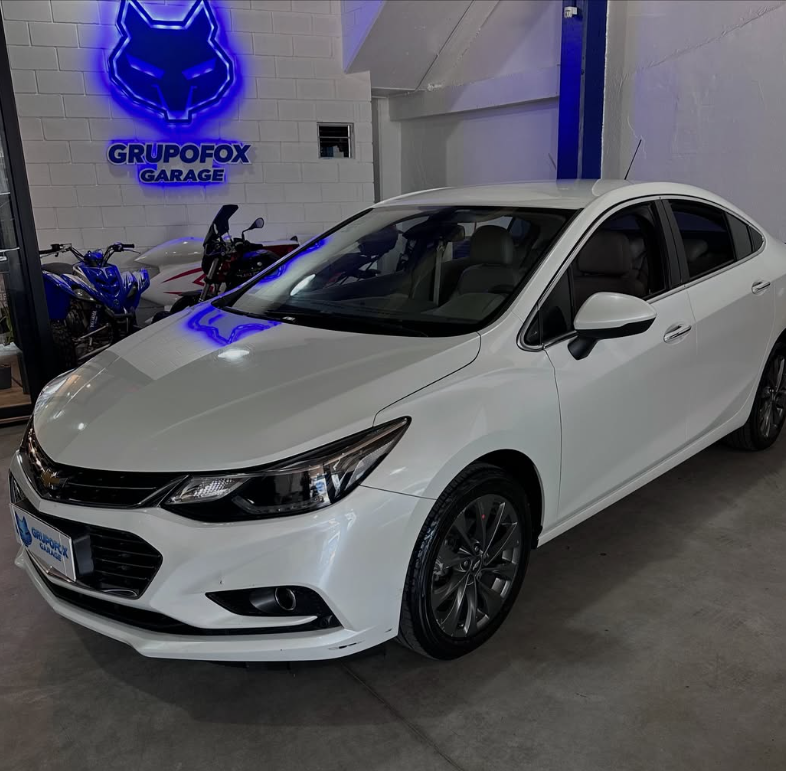 Chevrolet Cruze blanco en el salón de Grupo Fox Garage con el logo iluminado